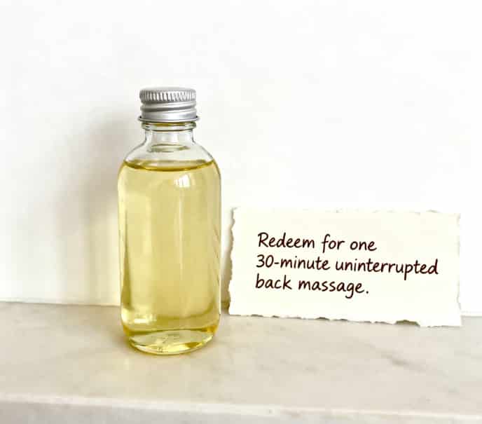 A bottle of massage oil next to a handwritten coupon for a relaxing back massage