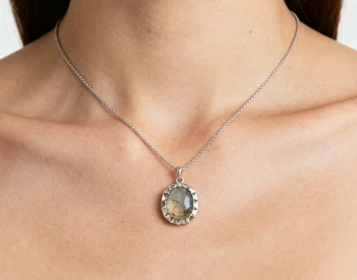 A close-up of a custom necklace pendant holding a gemstone from a meaningful location.