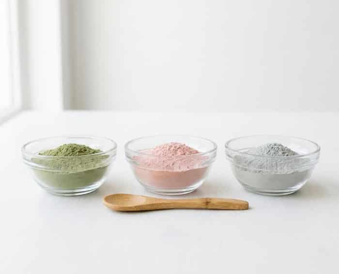 Bowls of colorful powdered face masks with wooden spoon