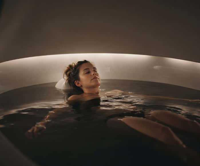 Woman floating calmly in sensory deprivation tank at wellness spa
