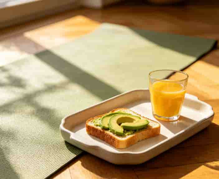 Yoga mat and a brunch tray with avocado toast and orange juice in a sunlit room