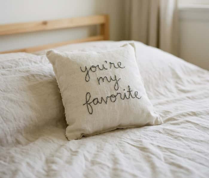 Custom embroidered linen throw pillow on bed