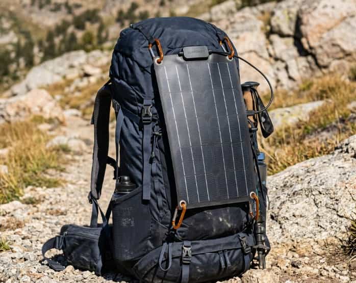 Flexible solar panel clipped to a hiking backpack in sunlight