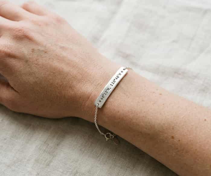 Silver bar chain bracelet engraved with custom coordinates worn on a wrist