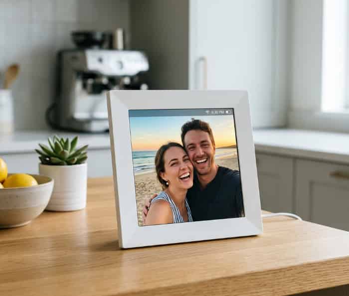 A long-distance digital picture frame showcasing a couple's beach photo in a modern kitchen