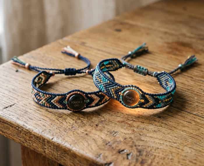 Two woven long-distance touch bracelets for couples on a wooden table, with one bracelet glowing softly