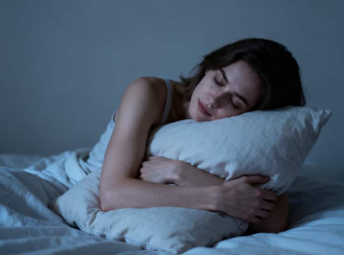 Woman hugging a voice-recordable pillow before sleep