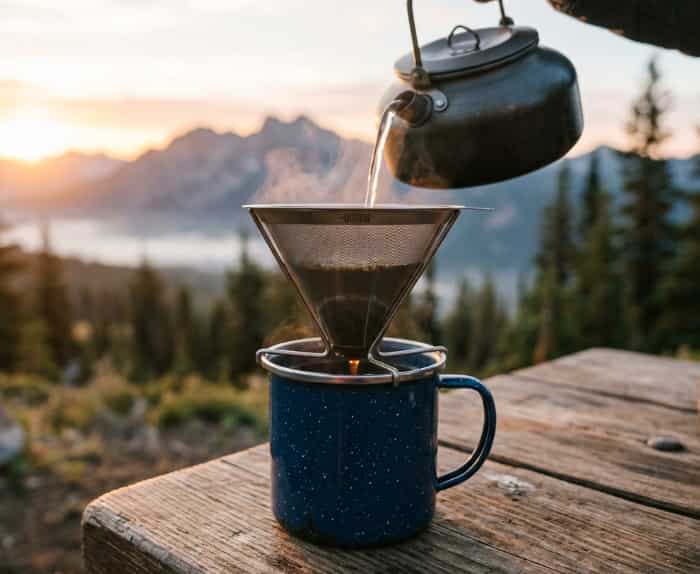 Titanium pour-over coffee dripper on a camp mug at sunrise