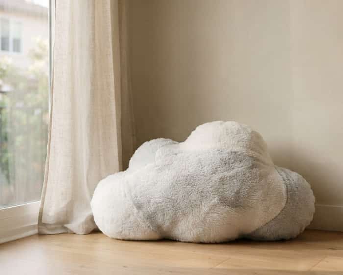 Fluffy cloud-shaped plush floor cushion next to a sunlit window