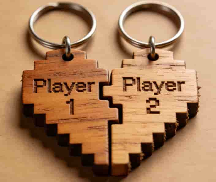 Two wooden keychains split into Player 1 and Player 2 halves forming a pixel heart when placed together