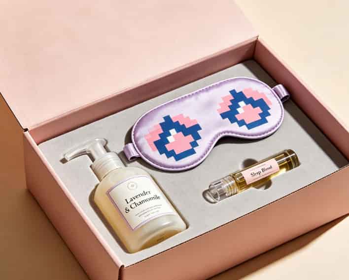 Self-care gift box with a pixel-art sleep mask, hand lotion, and vial-shaped roller bottle