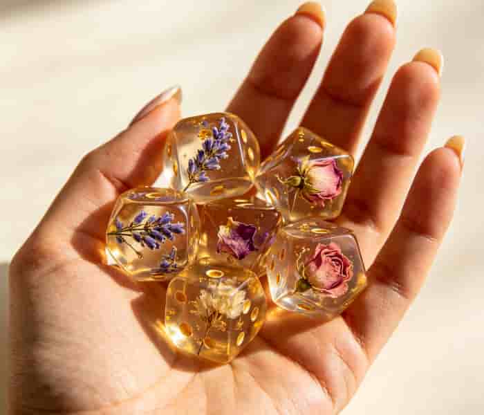 Handcrafted resin dice set with dried flowers inside, resting in an open palm