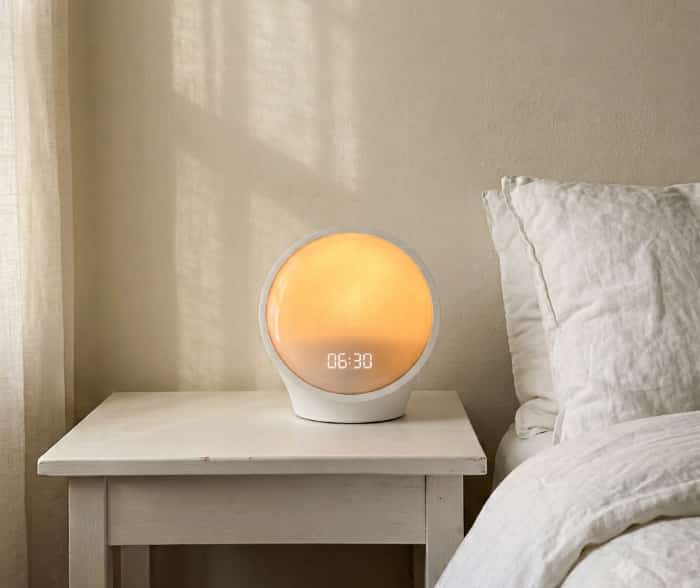 Smart sleep therapy sunrise lamp glowing softly on bedroom nightstand