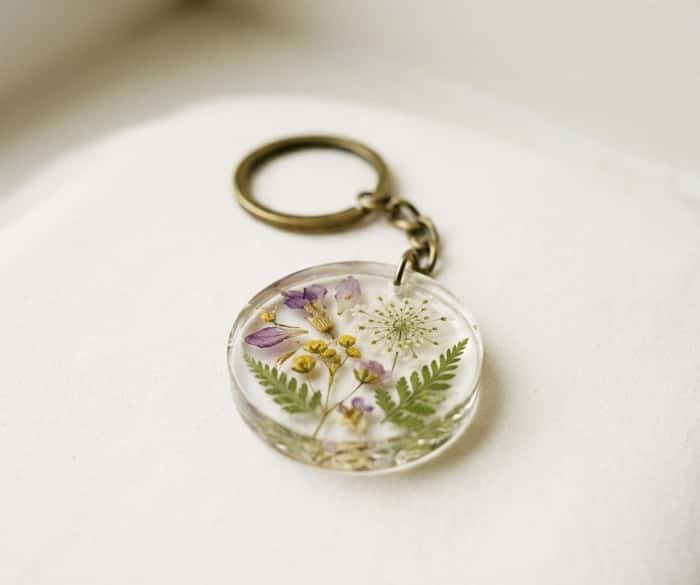Clear round resin keychain embedded with pressed pink flowers and botanical leaves