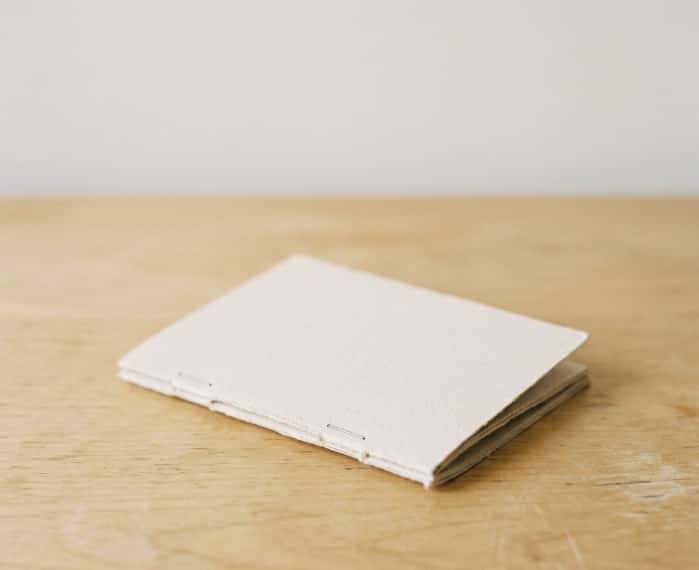 Stapled handmade paper book resting on a light wood table